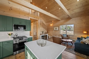 Interior de una cabaña de madera con cocina, comedor y sala de estar.