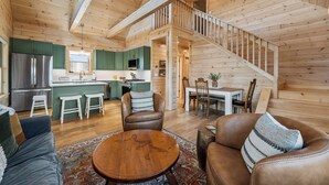 L’intérieur d’un chalet en bois comprend une cuisine, un coin repas et un escalier.