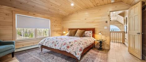 Une chambre à coucher dans une cabane en bois, avec un lit, une table de chevet, une lampe, une fenêtre et une porte.