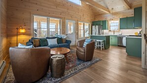 L’intérieur d’une cabane en rondins comprend un espace de vie, une cuisine et de grandes fenêtres.
