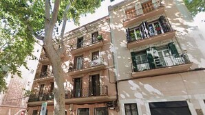 A multi-story building with balconies, a tree in the foreground, and a closed shutter on the ground floor. - Poble Nou - Llacuna by Interhome (Barcelona)