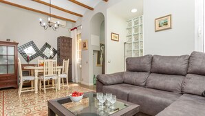 A living room with a sofa, a glass-top coffee table, a dining table with chairs, a chandelier, and a cabinet. - Poble Nou - Llacuna by Interhome (Barcelona)