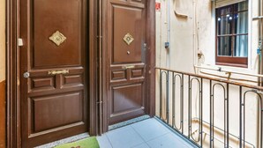 A set of wooden double doors with brass handles and a small window with a metal grille. - Poble Nou - Llacuna by Interhome (Barcelona)