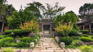 Ein traditioneller japanischer Garten mit Kieswegen, sorgfältig gestutzten Büschen und blühenden Pflanzen.
