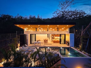 Ein modernes Haus mit Pool, Essbereich und Küche.