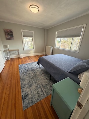 Une chambre à coucher avec un lit, un radiateur, une fenêtre et une porte.