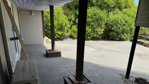 A covered outdoor area with a concrete floor, a wooden structure, and a potted plant.
