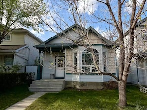 A two-story house with a front porch, a bay window, and a small front yard.