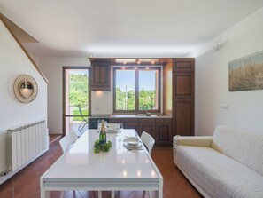 Eine moderne Küche mit Esstisch, einer Couch und Blick auf Grünflächen.