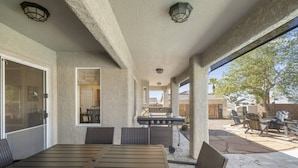 An outdoor patio with a table and chairs, a grill, and a view of the backyard. - Havasu Appaloosa - Pool, Parking, Central, Clean (Lake Havasu City)