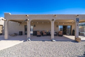 A covered outdoor patio with seating, a gravel ground, and a building with a beige exterior. - Villa Palmas - Pool, Comfort, Parking, ProjectorTV (Lake Havasu City)