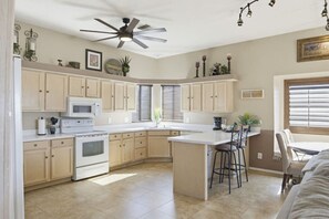 Une cuisine dotée d’un îlot central, d’appareils électroménagers intégrés et d’un ventilateur de plafond.