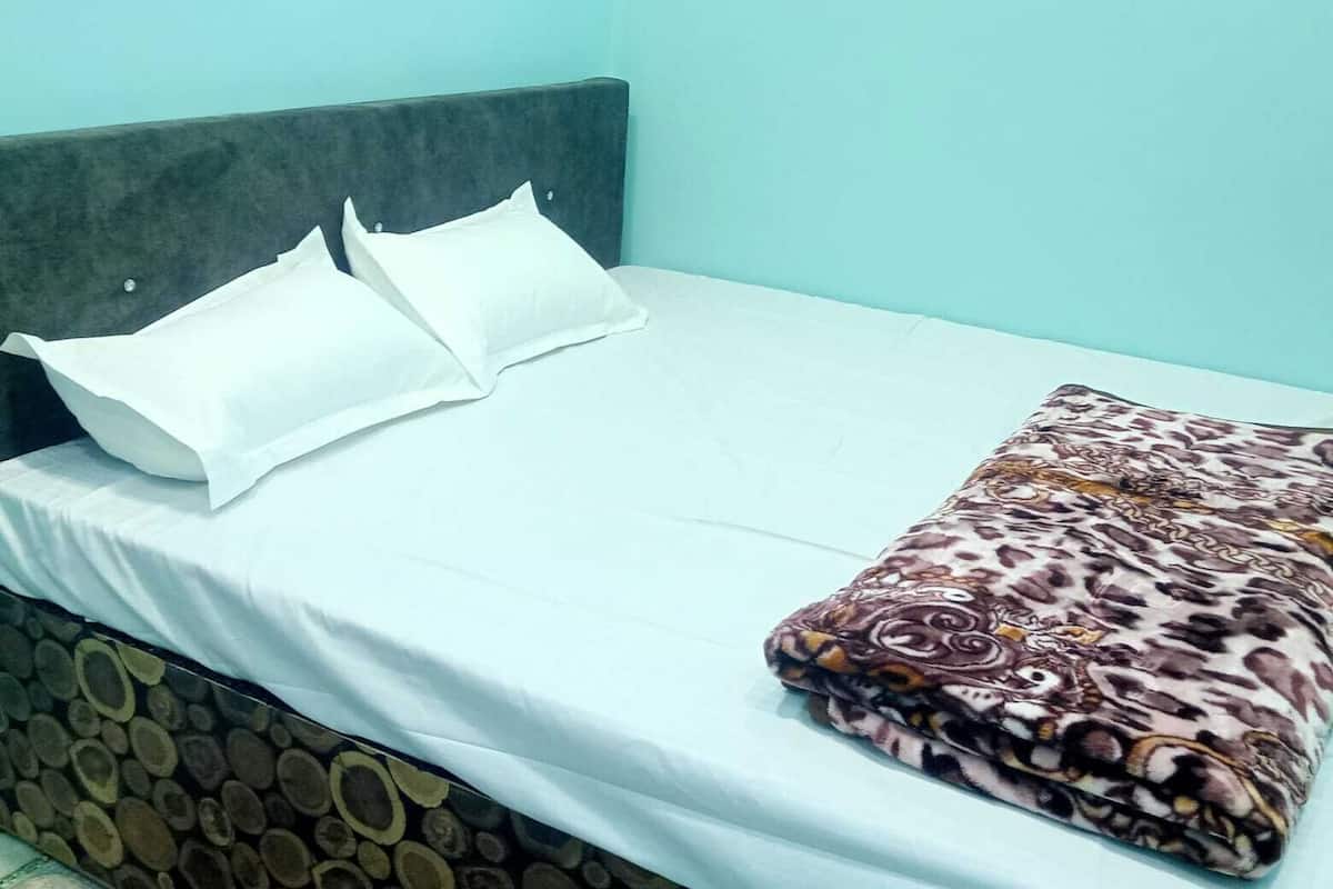 Un lit avec un drap blanc, deux oreillers et une couverture à motifs.