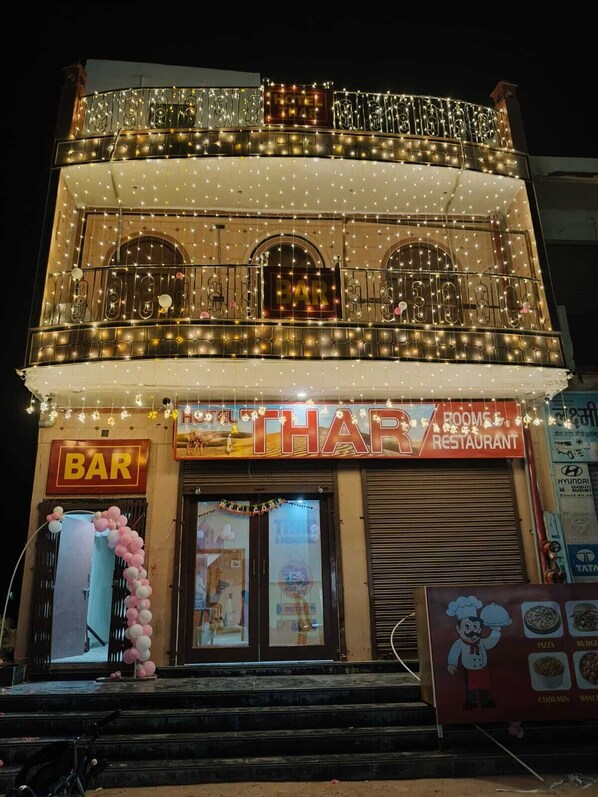 A two-story building with a bar and restaurant on the ground floor, featuring balconies with string lights.