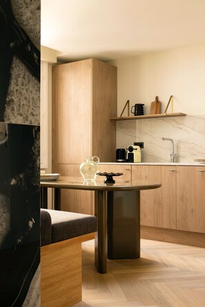 A modern kitchen with wooden cabinets, a marble countertop, and a built-in coffee machine. - Modern Appartement a/c 2br/4p - Montmartre (Paris)