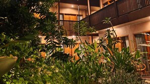 A multi-story hotel with a central courtyard, balconies, and lush greenery. - Home Dejavu (Gili Trawangan)