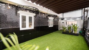 Uma cozinha moderna com azulejos hexagonais em preto e branco, armários brancos e piso de grama sintética verde.