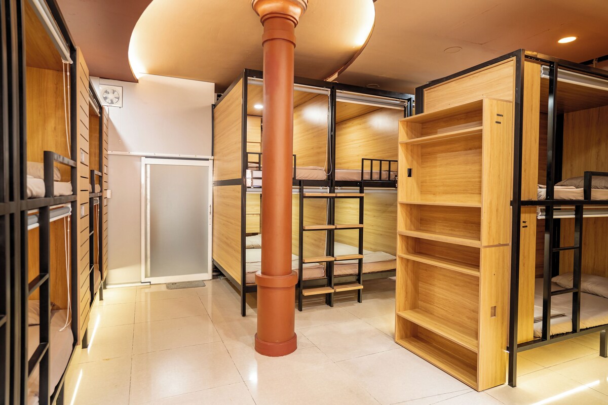 Una habitación con literas, una columna central y estanterías empotradas.