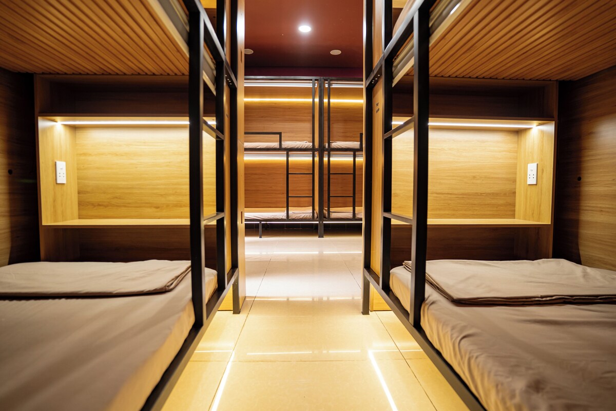 Habitación con literas, paredes de madera y una escalera central.
