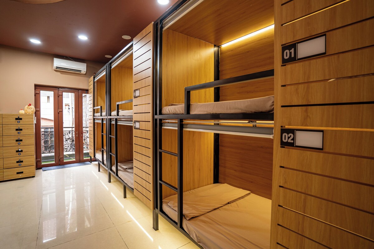 Habitación de hotel con literas, paneles de madera, un aparador de madera y una puerta que da a un balcón.