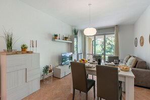 Ein moderner Wohnraum mit Essbereich, Fernseher und Sofa.