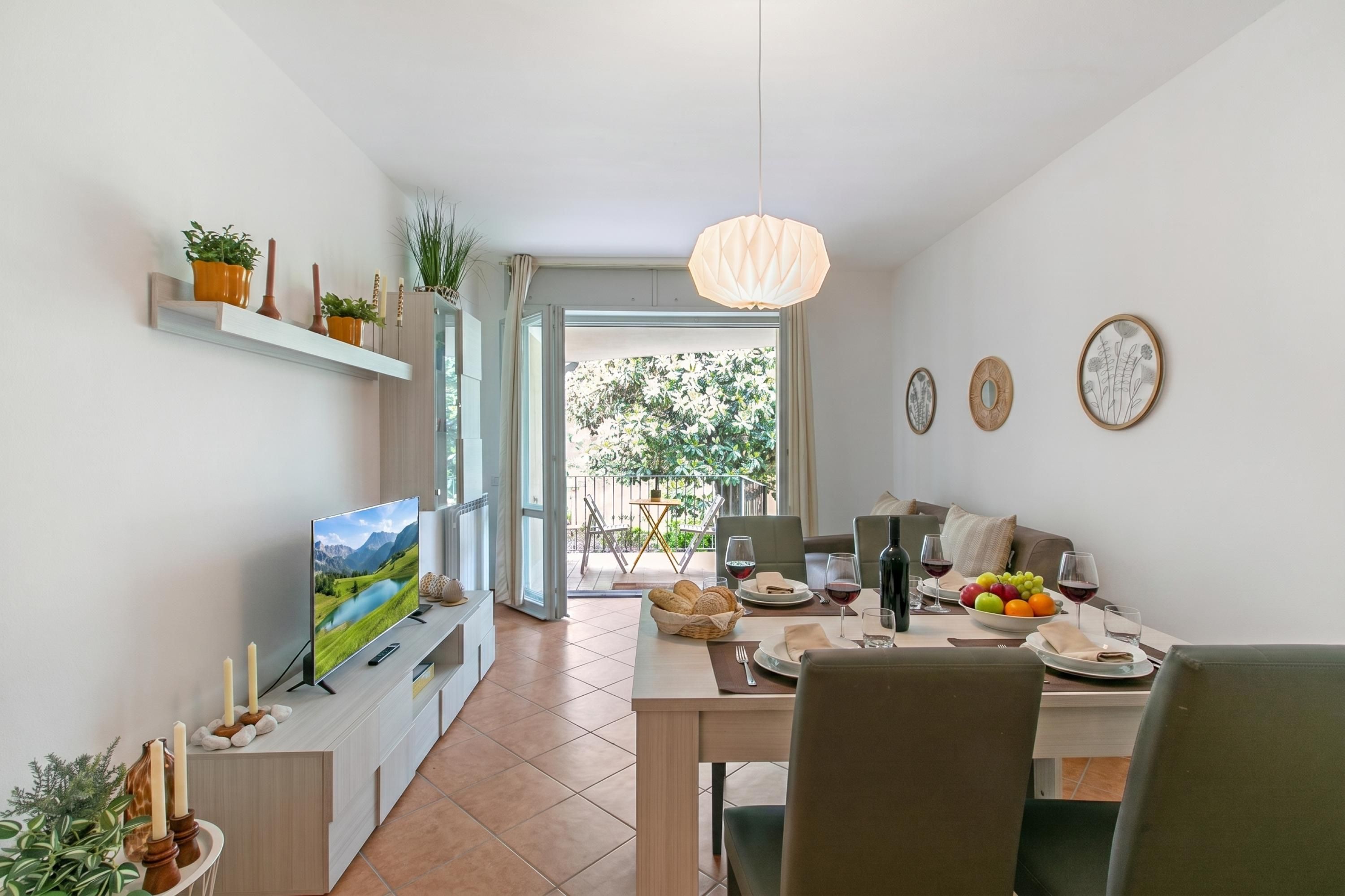 A modern dining area with a TV, dining table, chairs, and a view of the outdoors.