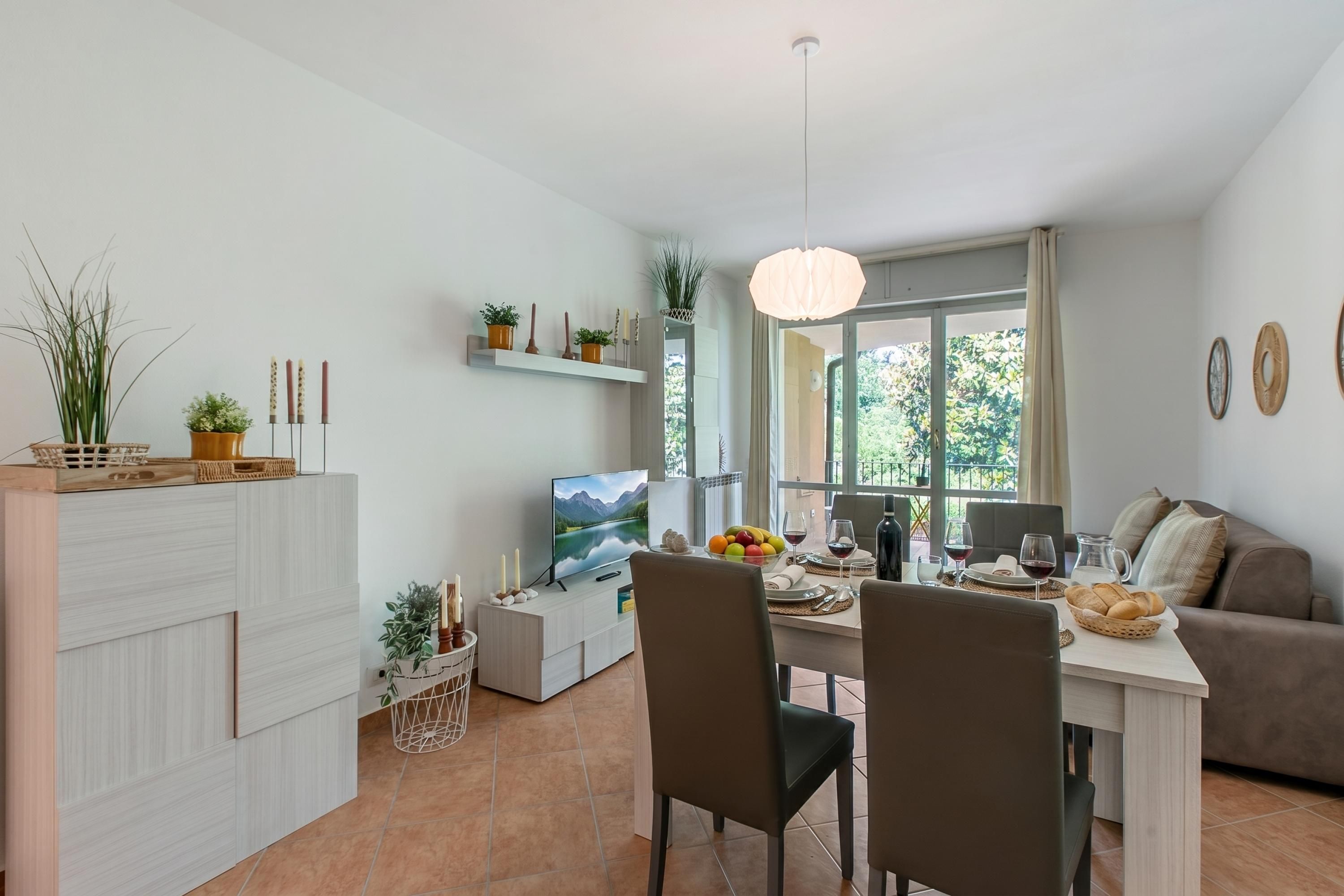 A modern living space with a dining area, a TV, and a sofa.