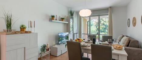 A modern living space with a dining area, a TV, and a sofa.