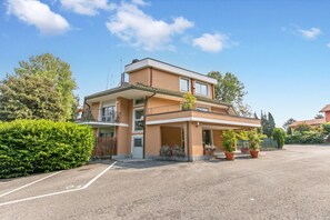 A two-story building with a balcony, a covered entrance, and a parking lot. - Residenza il Mulino: Lake Maggiore Ispra Apt With Terrace (Ispra)