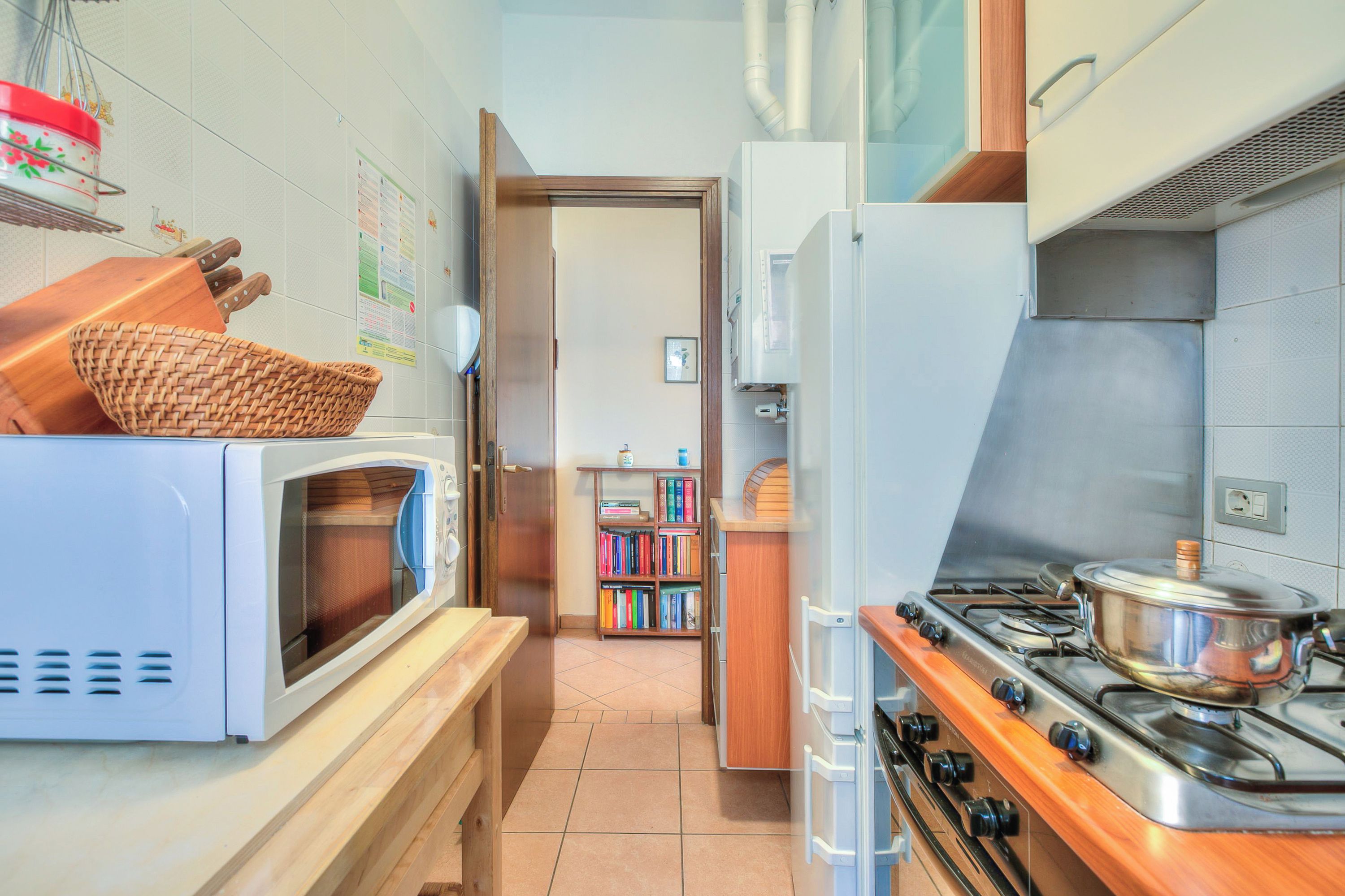 A compact kitchen with a microwave, stove, and wooden counter.