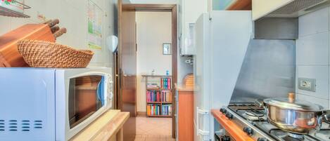 A compact kitchen with a microwave, stove, and wooden counter.