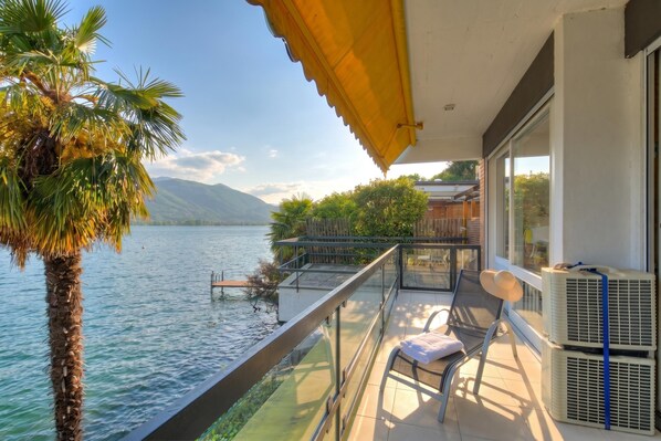 A balcony with a view of a lake, a chair, and air conditioning units. - Bellariva On The Lake With View Balcony (Collina d'Oro)
