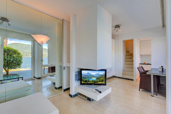 Ein modernes Wohnzimmer mit Flachbildfernseher, einem Essbereich und einer Treppe, die zu einer oberen Ebene führt.