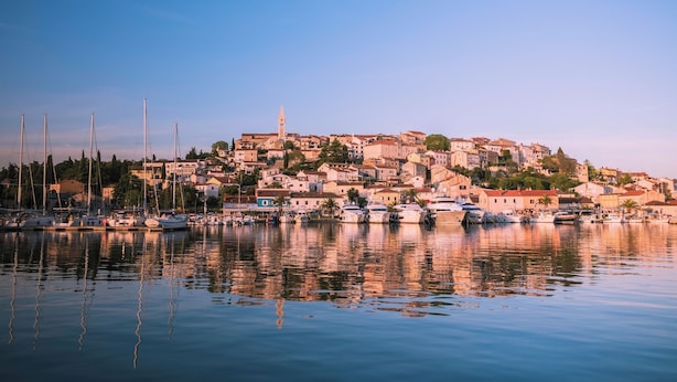 A coastal town with a marina, buildings, and a prominent tower. - Casa Rossa (Vrsar)