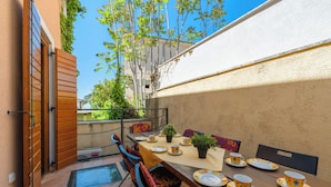 An outdoor dining area with a table set for four, chairs, and a potted plant. - Casa Rossa (Vrsar)