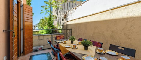 An outdoor dining area with a table set for four, chairs, and a potted plant.
