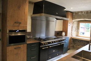 Eine Küche mit Backofen, Herd und einem Fenster zur Steinwand.