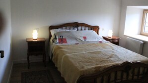 Camera da letto con un letto di legno, due comodini con lampade, un termosifone e una finestra.