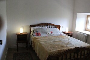 Ein Schlafzimmer mit einem hölzernen Bett, zwei Nachttischen mit Lampen, einem Heizkörper und einem Fenster.