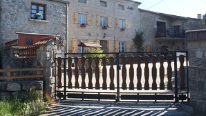 Un edificio in pietra con un cancello in legno, un balcone fiorito e una piccola finestra con una pianta.