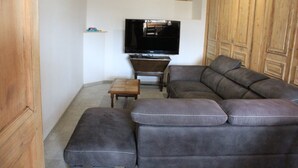 Un soggiorno con un divano componibile, una televisione e mobili in legno.