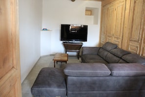 Ein Wohnzimmer mit einem Ecksofa, einem Fernseher und Holzmöbeln.