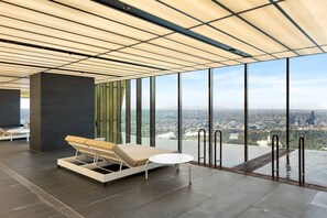A modern room with a large window, a lounge chair, and a small table. - 2BR Skyline Apartment with Pool & Views (Southbank)