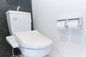 Eine moderne Toilette mit Bedienfeld, Toilettenpapierhalter und Wand-Bidet.
