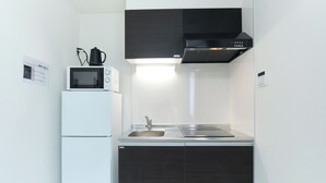 A compact kitchen with a microwave, sink, and black cabinets. - Fontaine Kamata by Tranova 2 (Ota City)