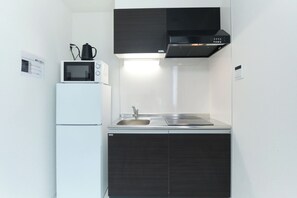 A compact kitchen with a microwave, sink, and black cabinets. - Fontaine Kamata by Tranova 2 (Ota City)