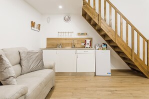 A modern kitchen with white cabinets, a wooden staircase, and a beige sofa. - THE HOUSE OF THE COURTYARD-apartment in the center of Naples. (Napoli)