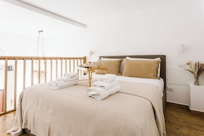 A bedroom with a bed, a nightstand, a small table with towels, and a window with a view. - THE HOUSE OF THE COURTYARD-apartment in the center of Naples. (Napoli)