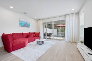 Ein modernes Wohnzimmer mit einem roten Sofa, einem Couchtisch und einem Fernseher auf einem Schrank.