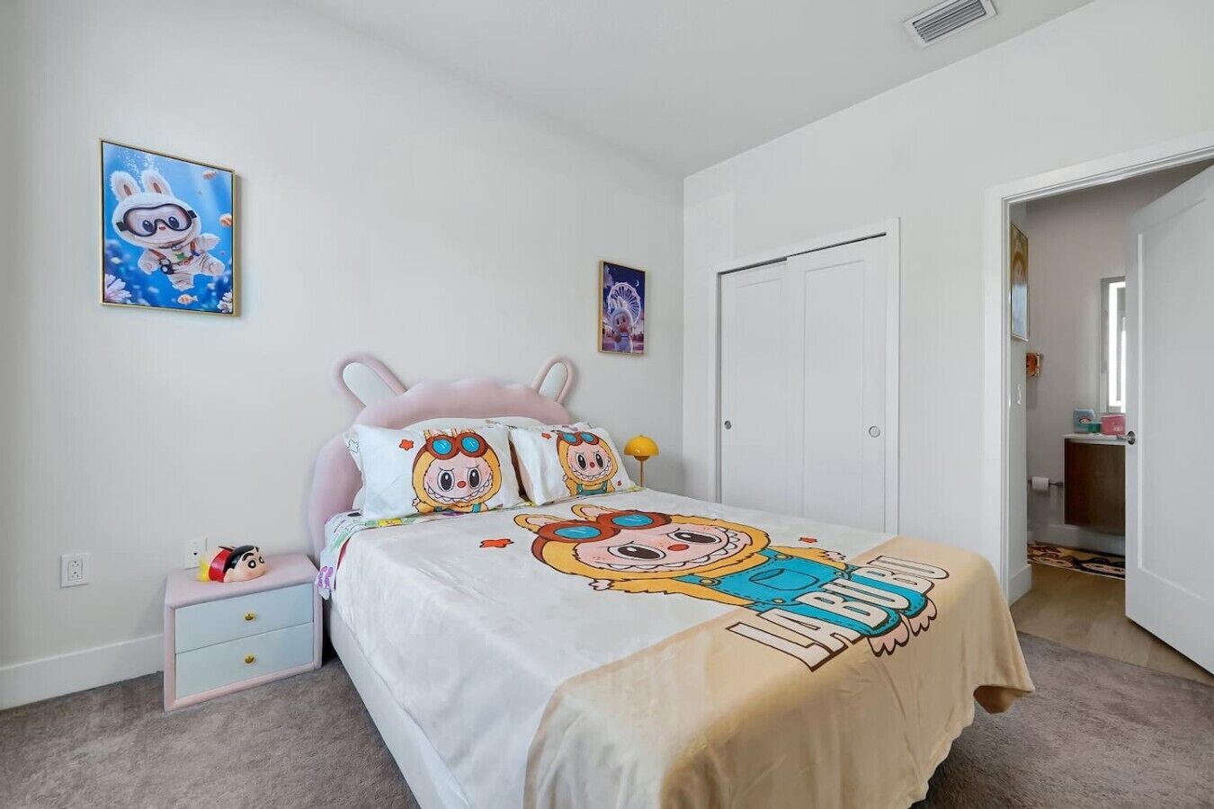 A bedroom with a bed, a nightstand, a dresser, and a door.